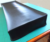 A black synthesizer dust cover lying on a flat surface, similar to what we make for the Roland Juno 106 Synthesizer.