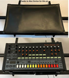 A black vinyl dust cover displayed on a Behringer RD-8 Rhythm Designer Drum Machine, with a view of the device's control pads and connectors.